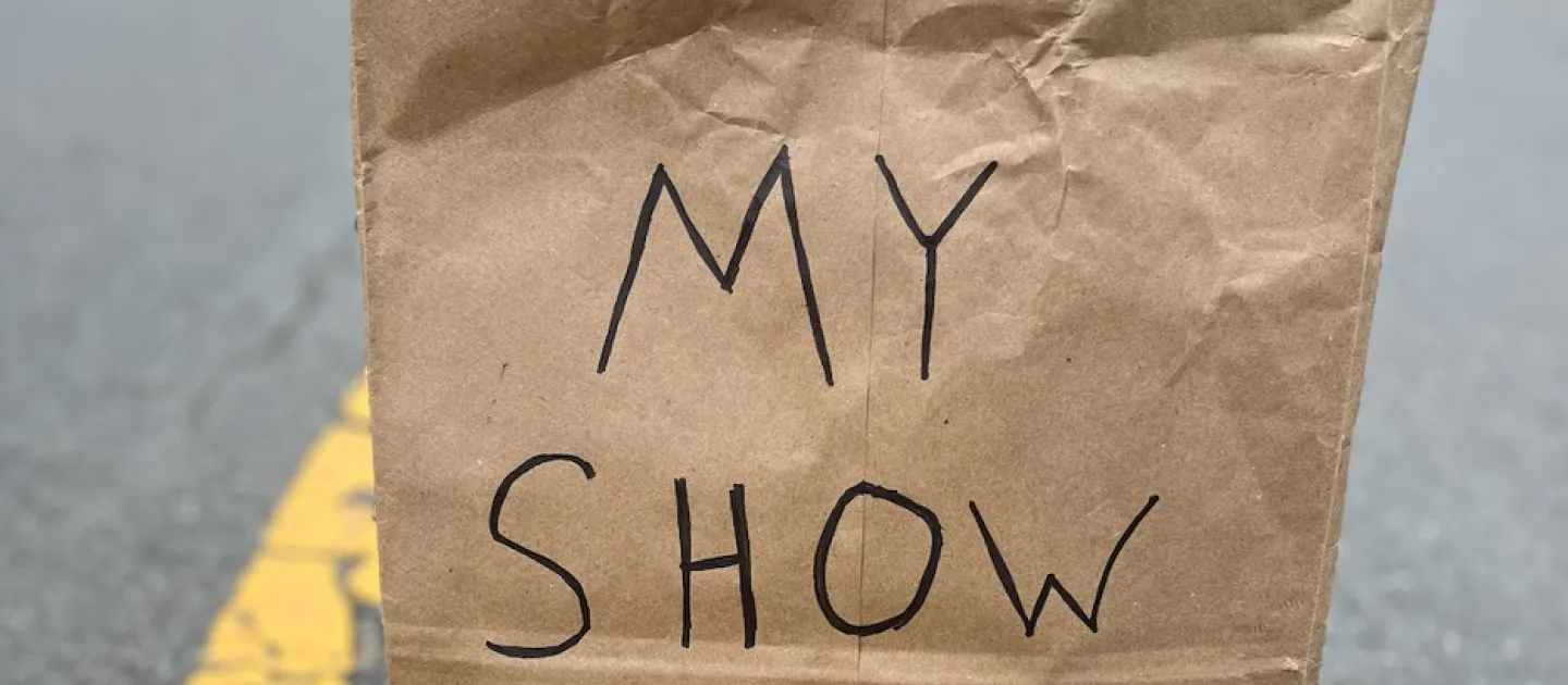 a brown paper bag labelled "My Show" sits on the yellow lines in the middle of a street