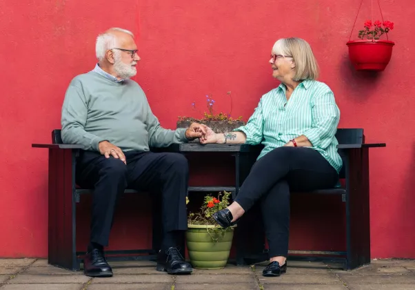 A QUIET LOVE main image, a couple holds hands at a table against a bright red background